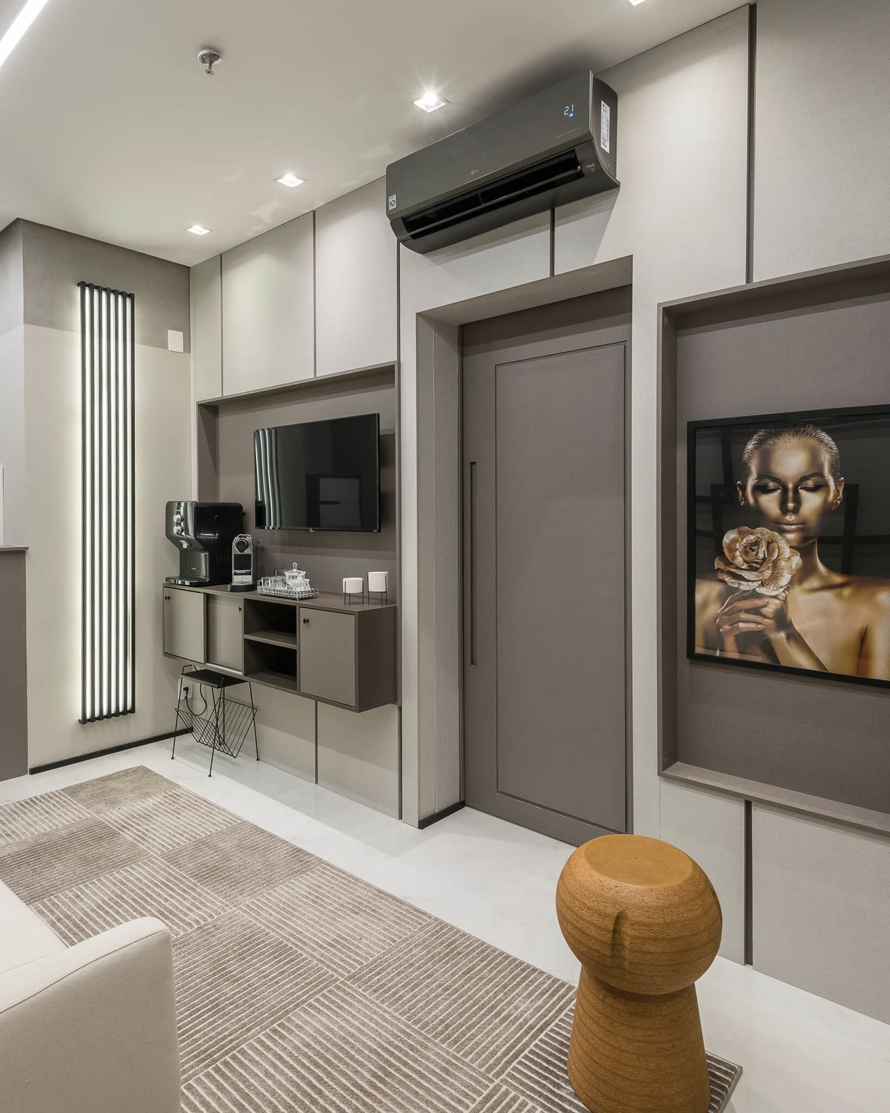 Sala de espera em tons de cinza com quadro dourado e banco de cortiça